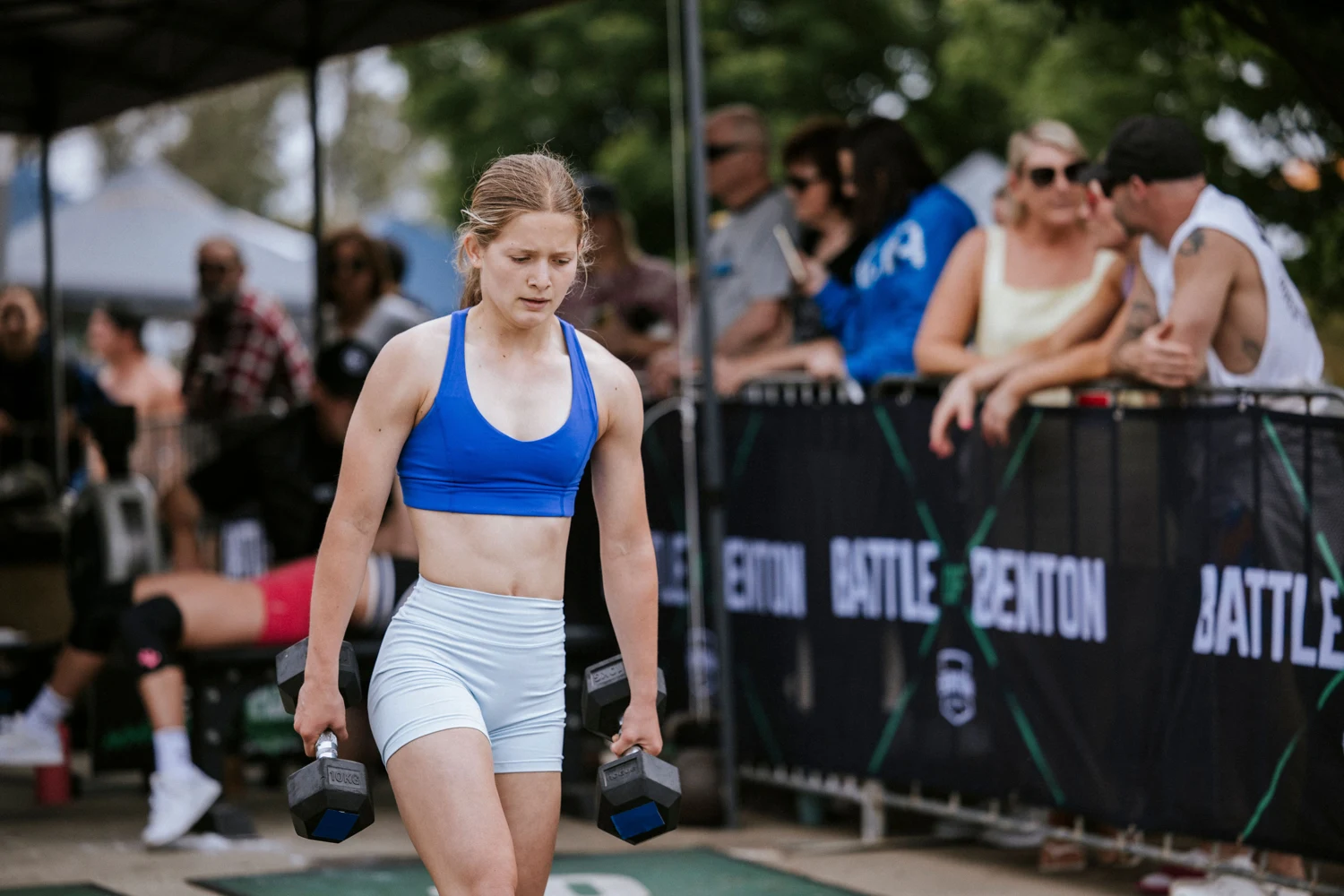 An athlete competing outdoors with spectators watching from behind the barriers